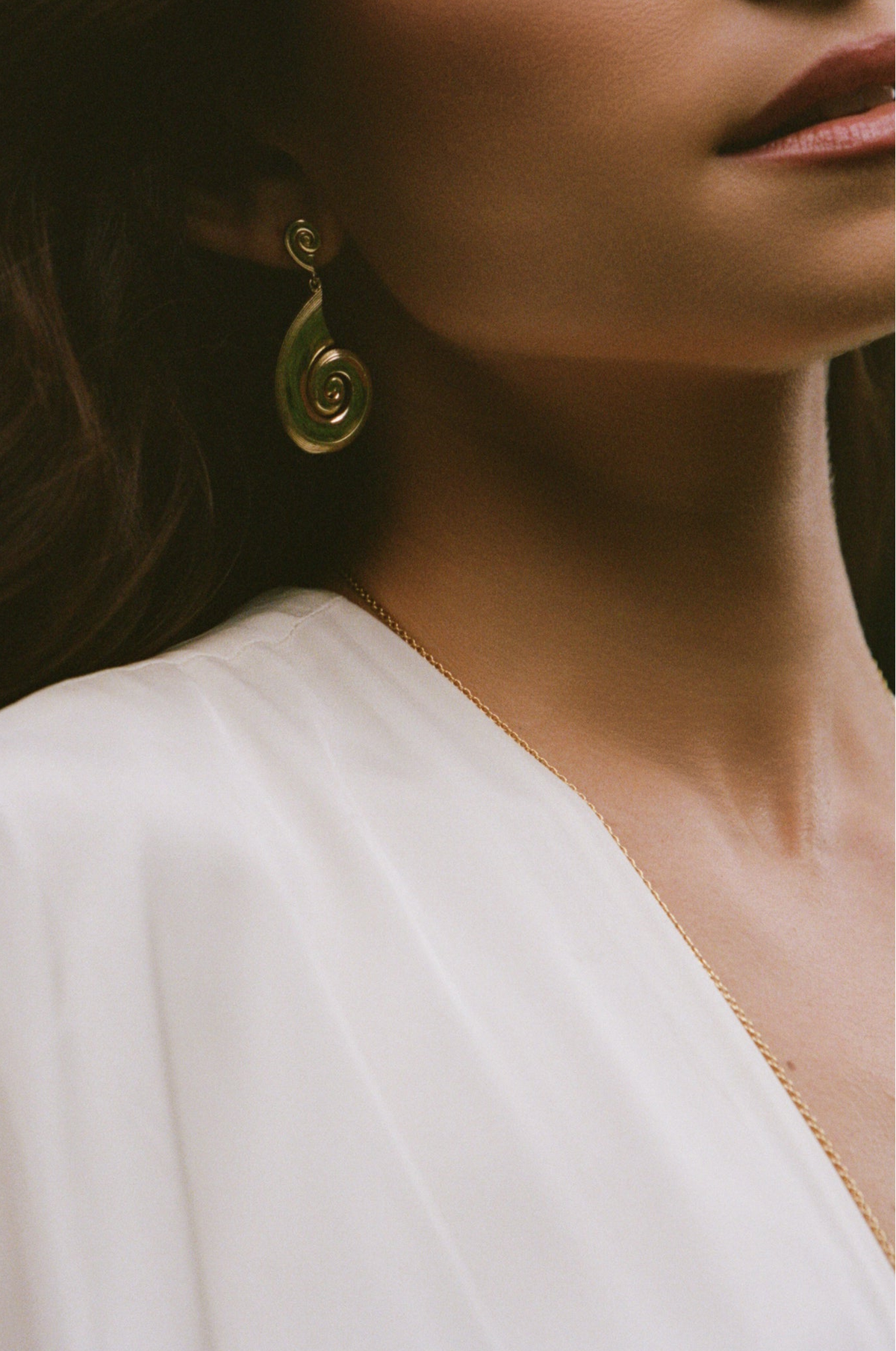 Earrings collection: model wearing a gold spiral drop earring
