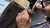 Jeweller's hands setting a stone into a piece at the workbench